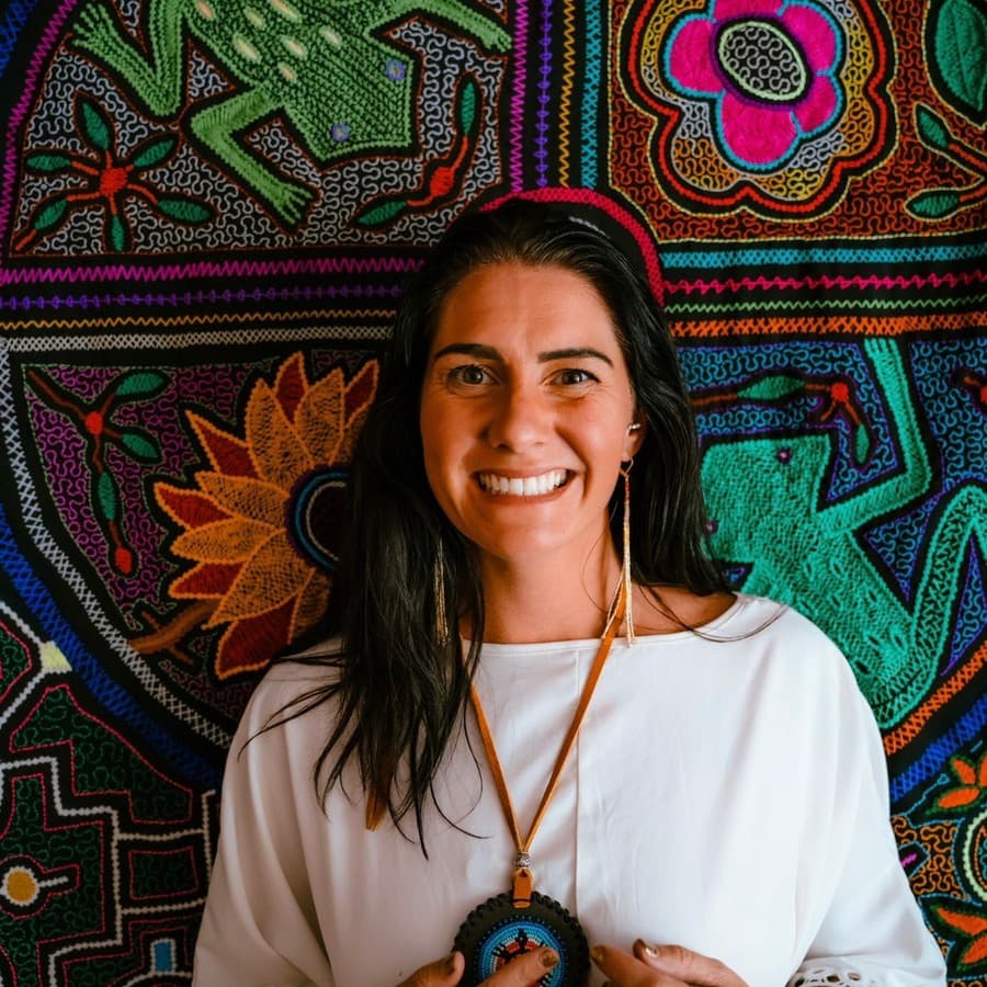 Kati smiling in white against embroidered cloth