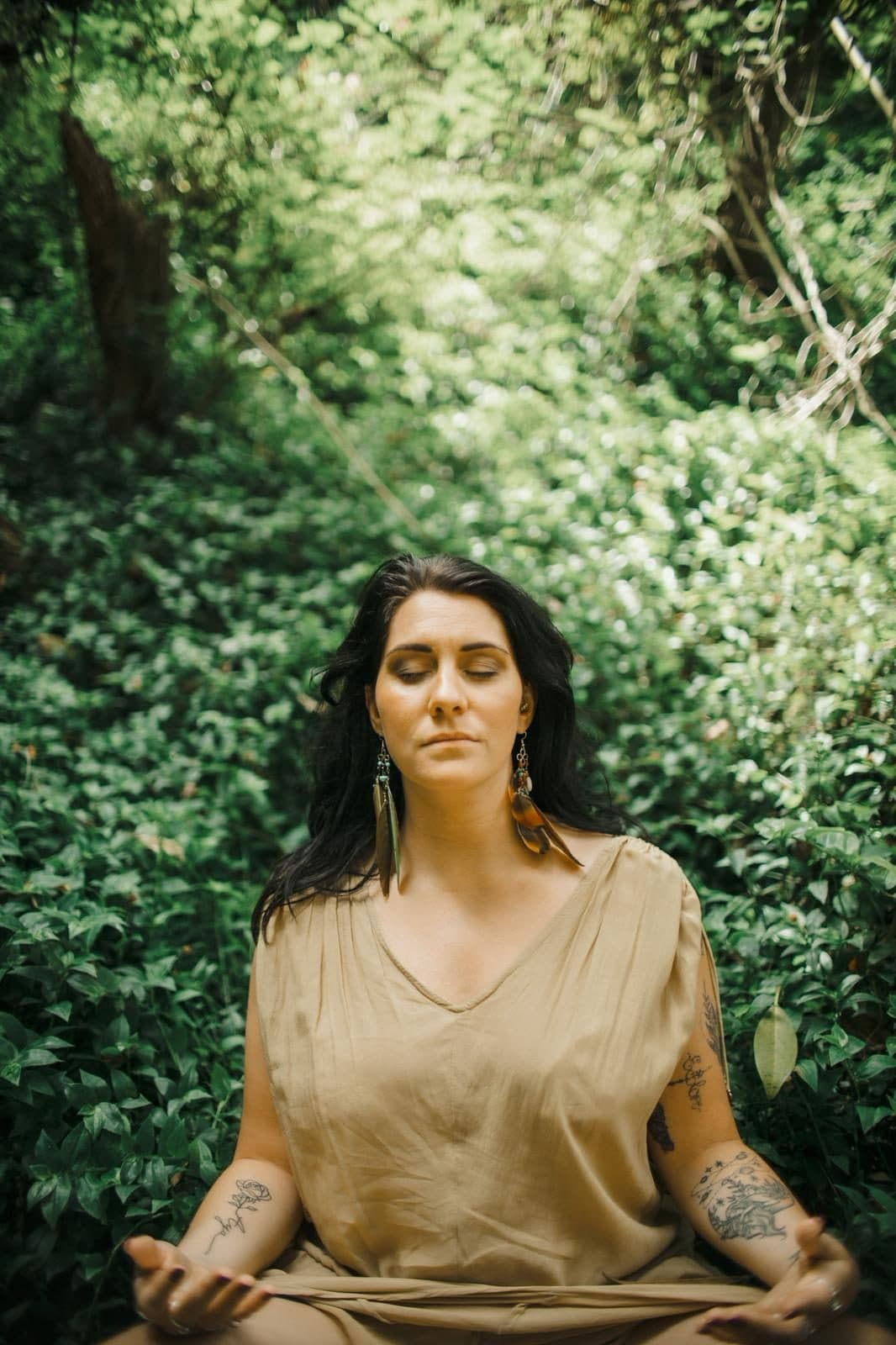 A woman sitting in stillness surrounded by dense green