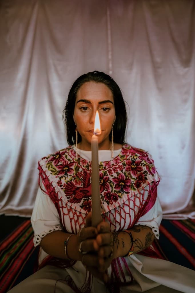 Kati holding a lit candle before her, in an embroidered shawl