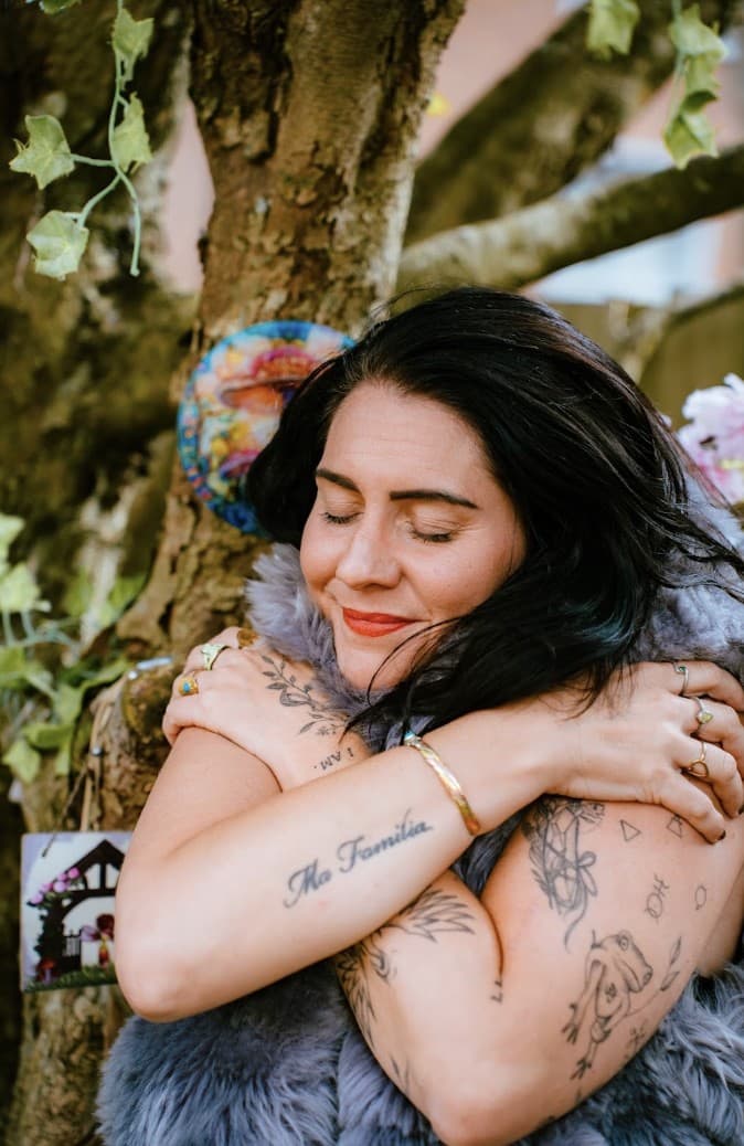 Kati hugging herself in a fur vest, eyes closed, smiling