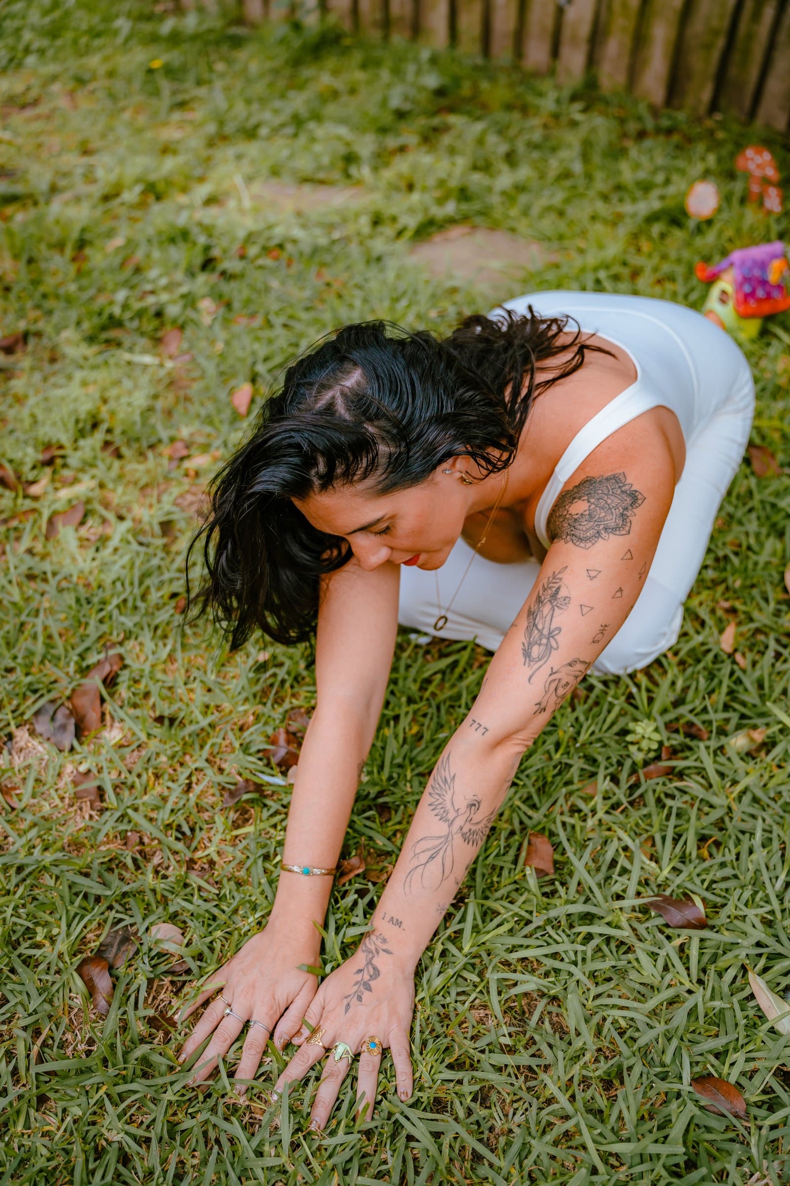 Kati on her hands and knees on the grass, head bowed to the earth